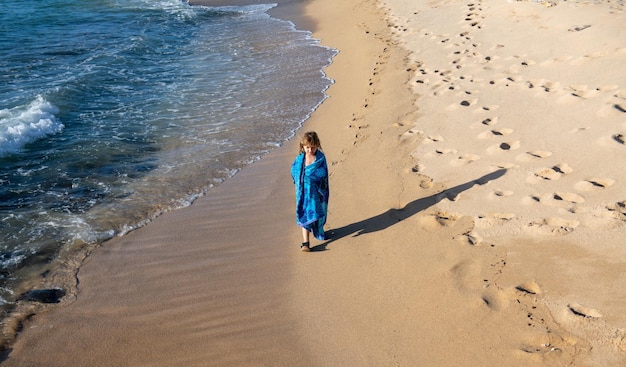 Kind in handdoek wandelen op het zomerstrand