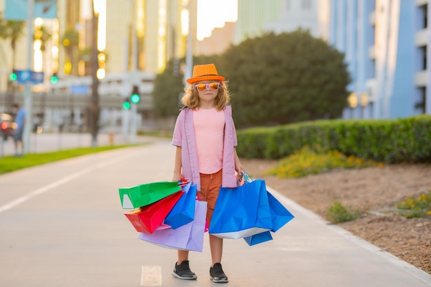 Kind in modekleding gaat winkelen kind met boodschappenpakketten buitenshopper kind met shoppin