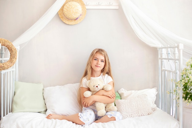 Kind in pyjama playning met teddybeer in de slaapkamer