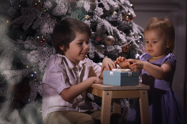 Kind in slimme kleren voor de kerstboom. Oudjaarsavond. Wachten op het nieuwe jaar.