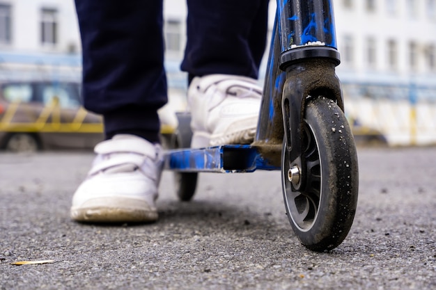 Foto kind in sneakers op een scooter op straat