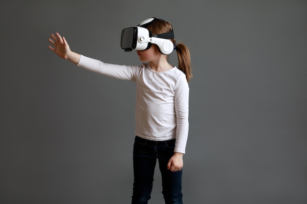 Kind in wit shirt met lange mouwen VR-bril dragen over grijs oppervlak.