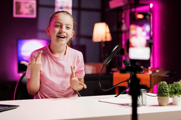 Foto kind influencer gesponsord door het bedrijf om hun nieuwe online campagne aan kinderen te promoten kind voldoet aan het merk partner contract door reclame branding en slogan opnemen met telefoon op driepoot