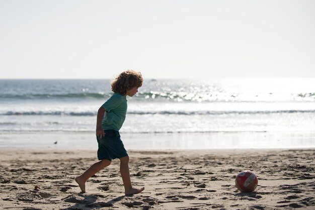 Kind jongen voetballen op zandstrand