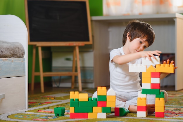 Kind jongetje spelen met houten kubussen speelgoed in kinderdagverblijf thuis of kinderdagverblijf