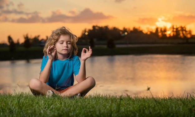 Kind kalmte en ontspanning op de natuur achtergrond klein kind mediteert terwijl het beoefenen van yoga vrijheid en c