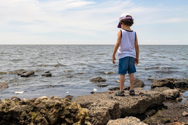 Kind kijkt naar de vervuilde rivier vanaf het milieuconcept aan de kust