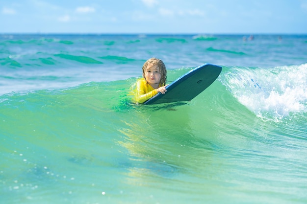 Kind, kleine surfer, leert rijden op surfplank op zeegolven, gelukkig kind dat in de zee speelt, kind heeft