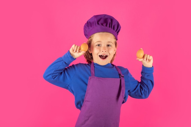 Kind kok houdt eieren Koken kinderen Chef jongen jongen in vorm van kok Kind jongen met schort en chef hoed bereiden van een gezonde maaltijd op studio geïsoleerde achtergrond Kookproces