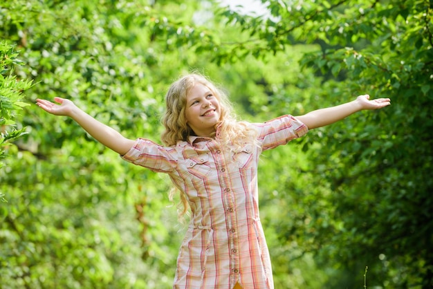 Foto kind lachend meisje mooi lang krullend haar natuur achtergrond lopen frisse lucht goed humeur zomervakantie ranch meisje natuurlijke zorg schattig meisje buitenshuis cosmetica concept gelukkige jeugd