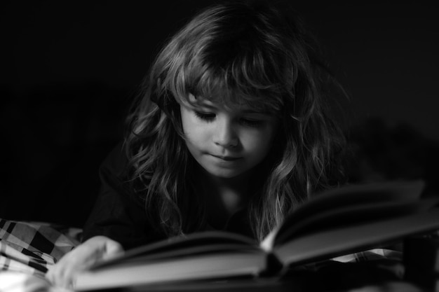 Kind leest een boek in bed voordat hij gaat slapen kleine jongen liggend op bed leesboek thuis bedti