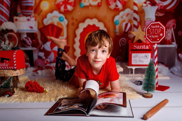 Kind leest een boek op kerstnacht Happy xmas en Nieuwjaar wintervakantieconcept met kopieerruimte voor tekst op rode achtergrond