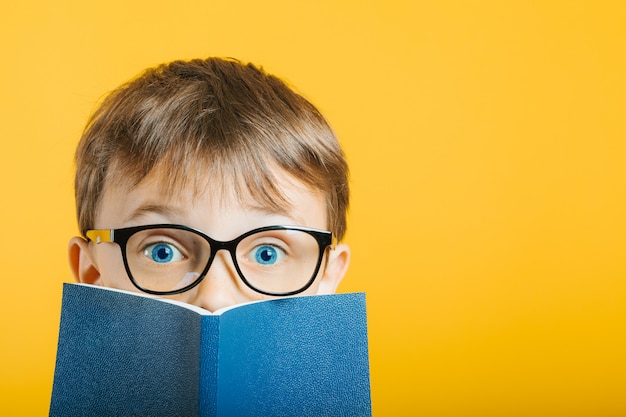 Kind leest een boek tegen een lichte muur