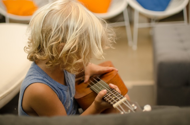 Foto kind leren hoe een houten ukelele te spelen.