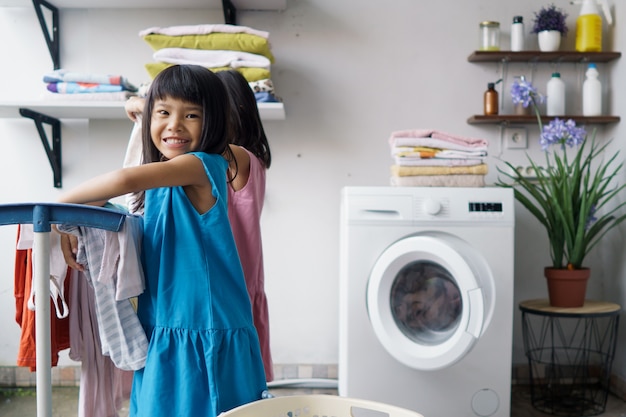 Kind leuk gelukkig klein meisje om kleren te wassen en lacht in de wasruimte