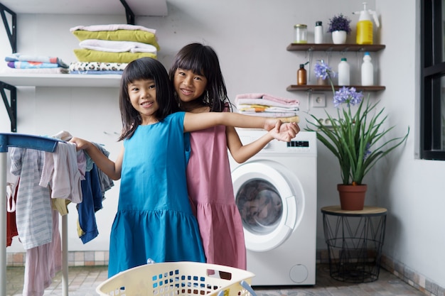 Kind leuk gelukkig klein meisje om kleren te wassen en lacht in de wasruimte