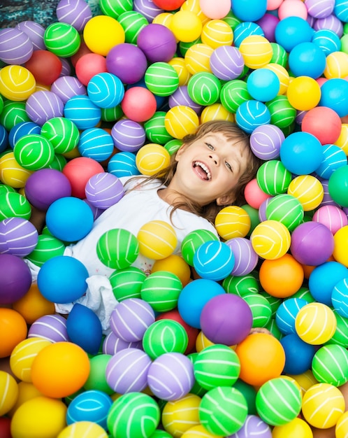 Kind liggend in zwembad met plastic ballen