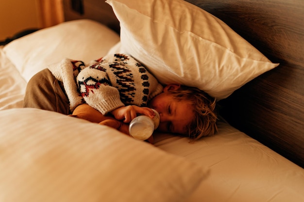 Kind liggend op het bed melk drinken uit babyfles