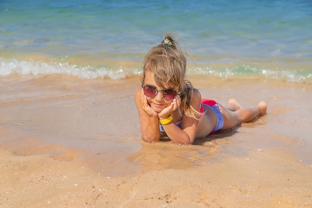 Kind ligt in het zand op het strand