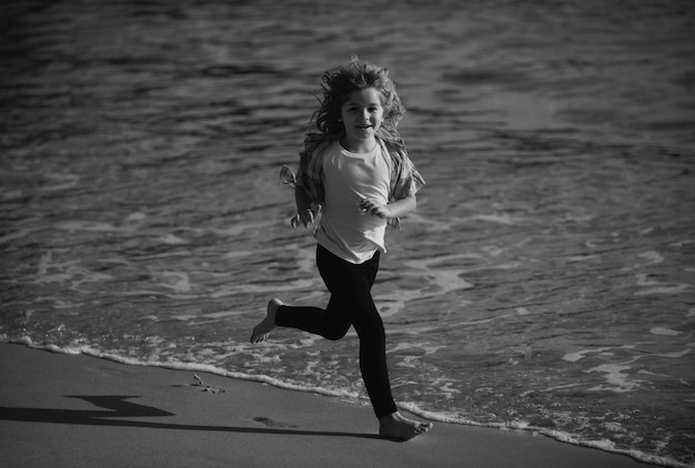 Kind loopt door water dicht bij de kust langs het zeestrand een jongen rent langs de zeekust rust uit