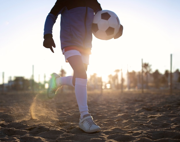 Foto kind loopt op het strand met voetbal