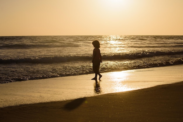 Kind loopt op het zandstrand bij zonsondergang Kindjongen heeft plezier op het strand Zomervakantie en gezonde levensstijl voor kinderen