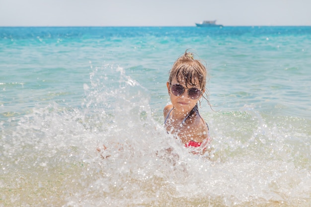 Kind maakt spray op de zee