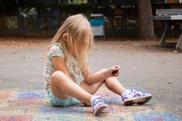 Kind meisje blonde voorschoolse leeftijd wordt gespeeld zittend op de stoep