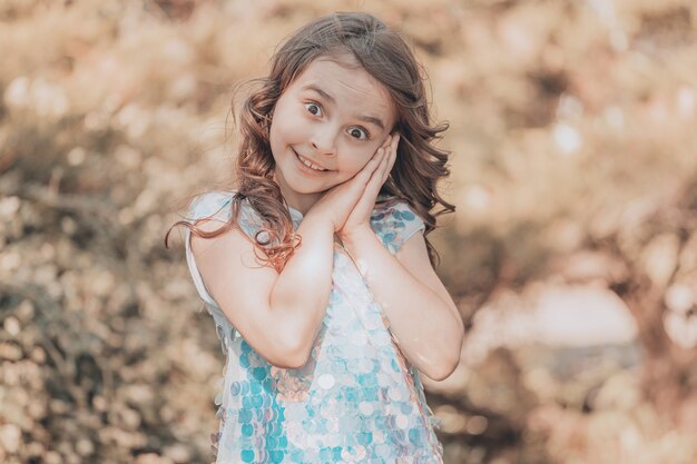 Kind meisje brunette met donker haar in een glanzende jurk in de natuur. vanille kleuring. Hoge kwaliteit foto