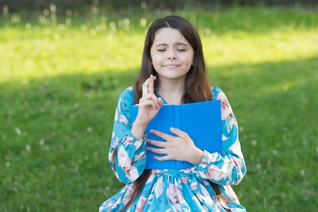 Kind meisje buiten ontspannen met boek voorbereiden op examens concept