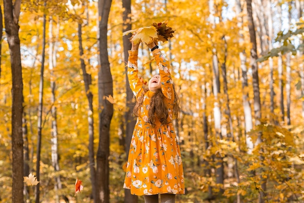 Kind meisje dat herfstbladeren gooit op herfst natuur plezier vrije tijd en jeugd concept