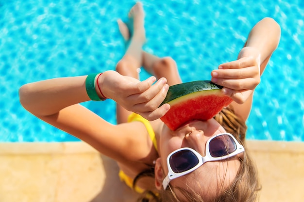 Kind meisje eet watermeloen bij het zwembad