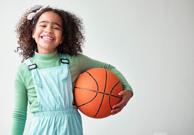 Kind meisje en gelukkig met basketbal op witte achtergrond met sport voor training en fitness in Brazilië Vrouwelijke persoon portret en glimlach of opgewonden met hobby op mockup ruimte voor kinderontwikkeling