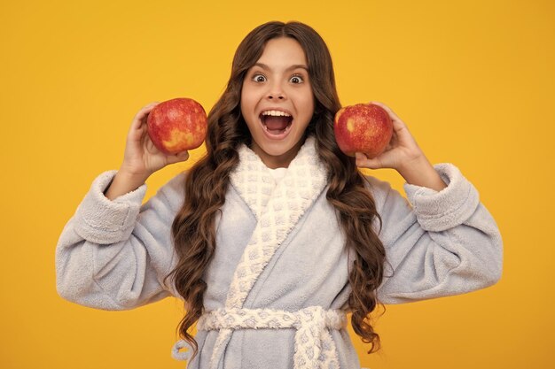 Kind meisje met appel over geïsoleerde gele studio achtergrond Tennager met fruit Portret van gelukkig grappig lachend tienermeisje