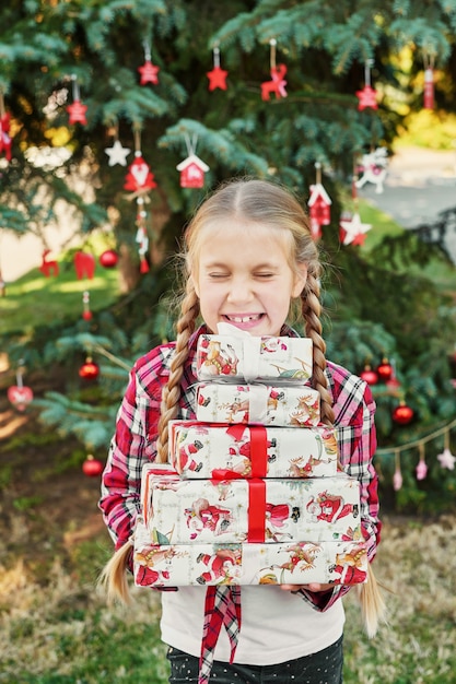 kind meisje met geschenken in de buurt van een kerstboom,