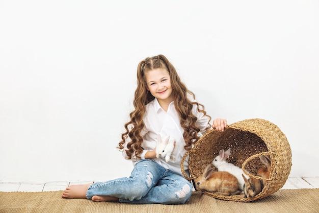 Kind meisje mooi schattig vrolijk en blij met kleine dieren konijnen op witte muur achtergrond