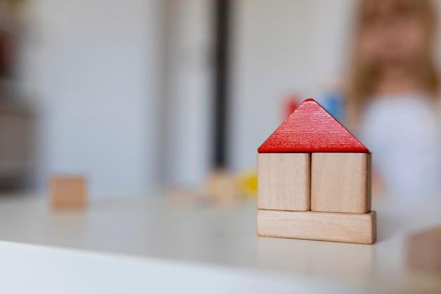 Kind meisje spelen met kleurrijke houten speelgoed bouwstenen. Klein kind bouwt toren of huis thuis of kinderopvang. Educatief speelgoed voor jonge kinderen. Bouwblok voor baby of peuter