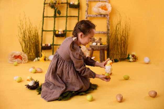 Kind meisje spelen met paaseieren en kuiken traditionele paasdecoratie in landelijke stijl