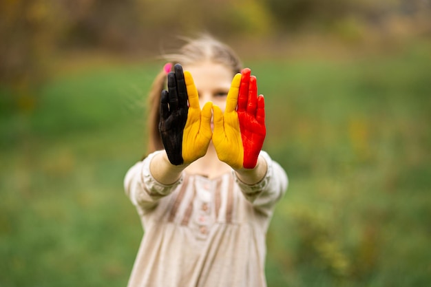Foto kind meisje toont handen geschilderd in belgische vlagkleuren focus op handen