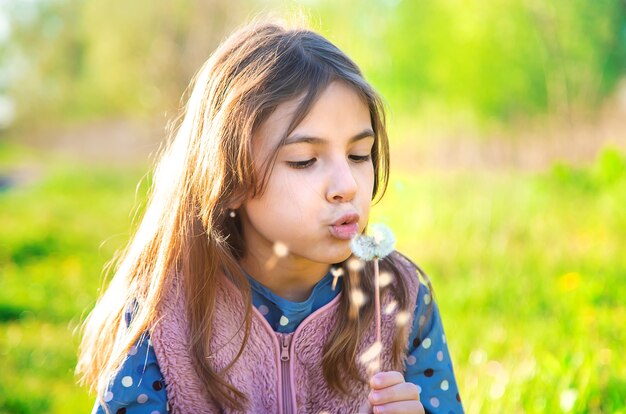 Kind meisje waait paardebloem in het voorjaar