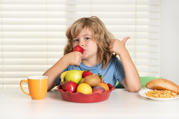 Kind met aardbeien zomervruchten portret van kind eet vers gezond voedsel in de keuken thuis kid