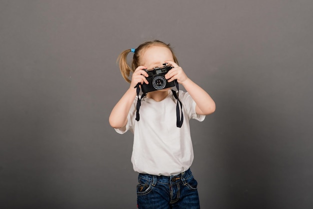 Kind met camera. Klein meisje fotograferen in studio achtergrond