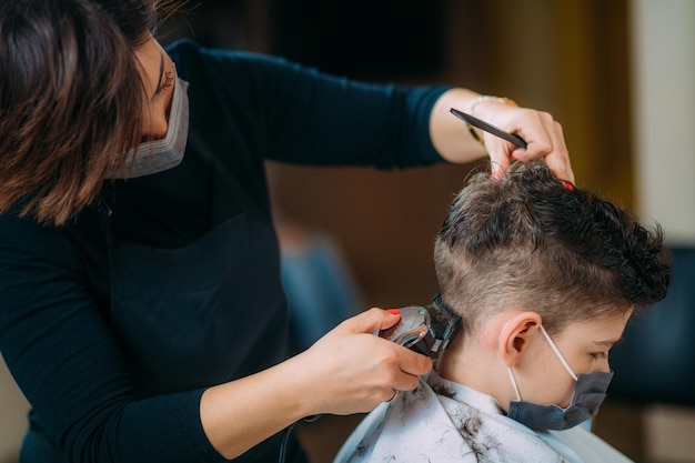 Kind met een beschermend masker Haircutting in kapsalon