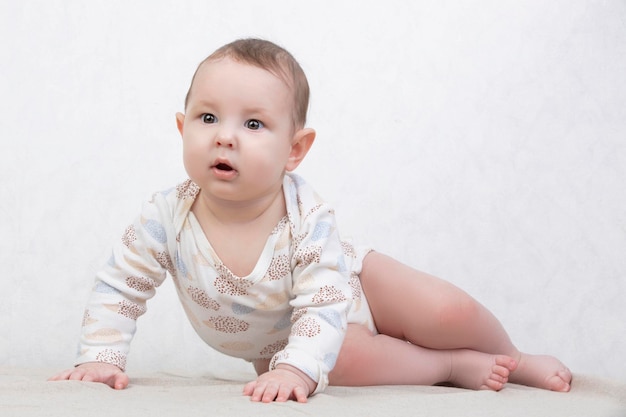 Kind met een glimlach op een witte achtergrond Een gezonde zes maanden oude jongen ligt op het bed