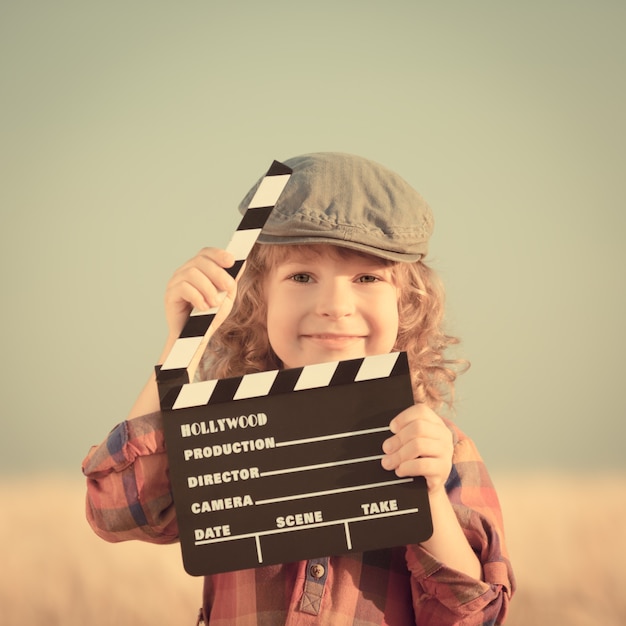 Foto kind met filmklapper tegen de zomerhemelachtergrond