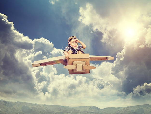 kind met kartonnen vliegtuig vliegen in de lucht