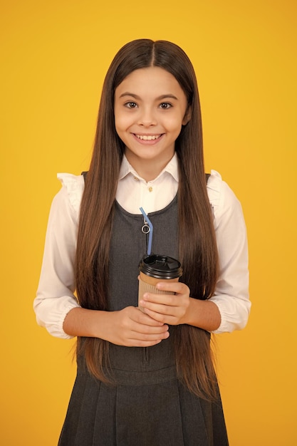 Foto kind met koffie of theekopje geïsoleerd op gele studioachtergrond tienermeisje met afhaaldrank