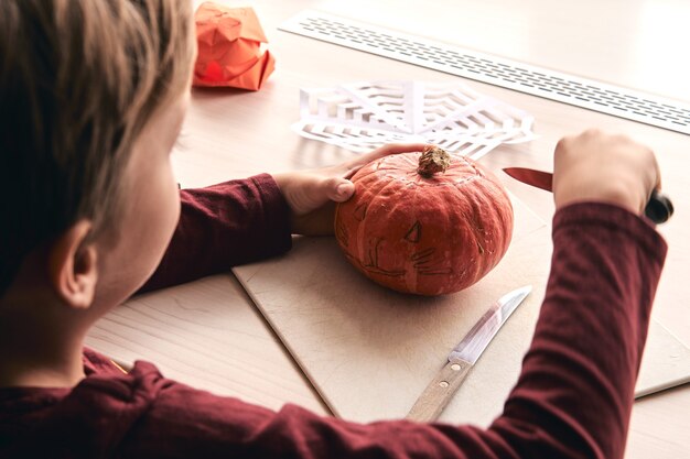 kind met mes snijdende pompoen of jack-o-lantern. Moeder tijd doorbrengen met zoon samen.