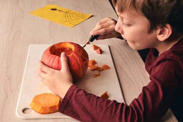 kind met mes snijdende pompoen of jack-o-lantern. Moeder tijd doorbrengen met zoon samen.