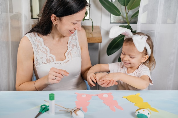 kind met moeder Pasen cadeau met konijn van papier maken